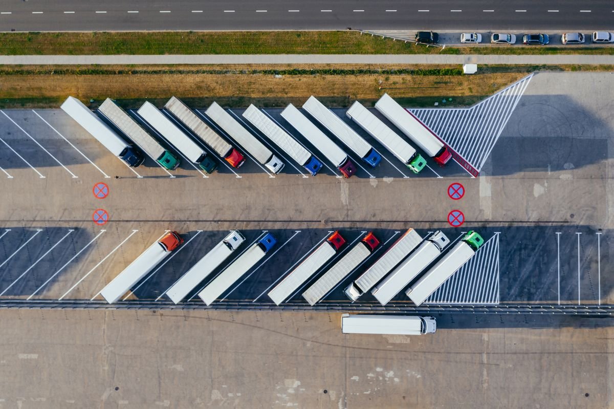 Aerial view of trucks parked at a rest stop beside a European motorway