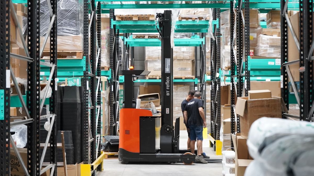 Forklift moving pallets between warehouse racking aisles