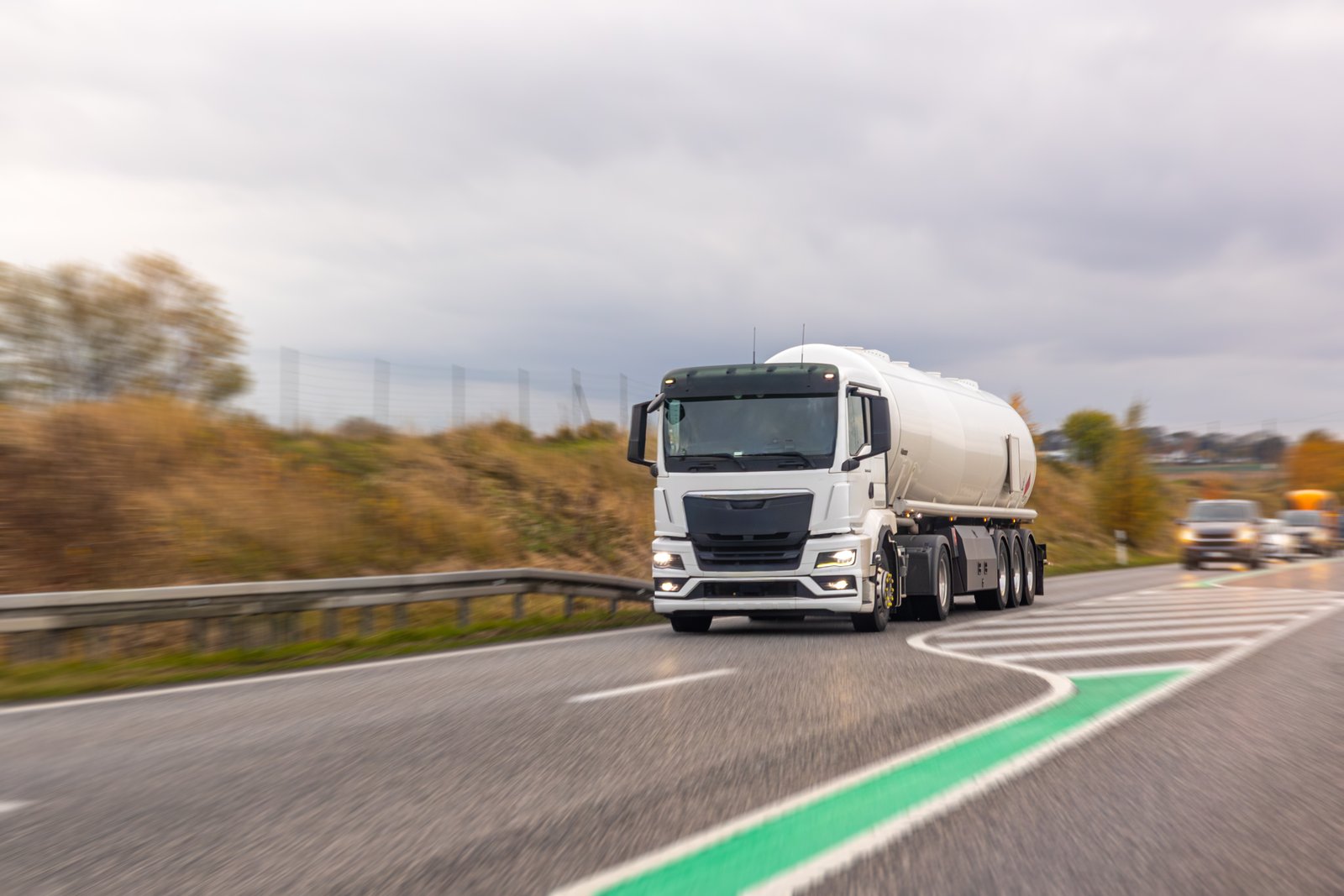 White tanker truck on a highway curve with motion blur under cloudy daylight